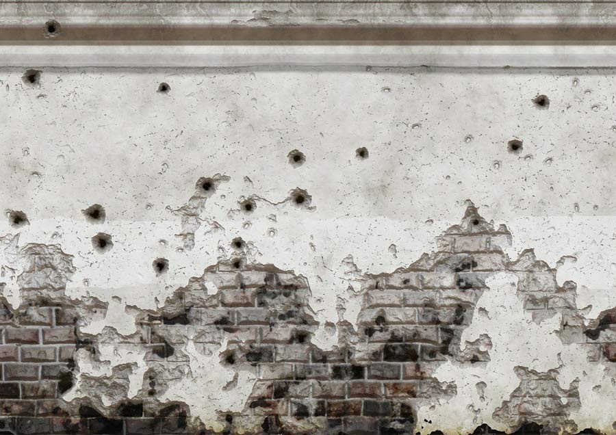 Weathered plaster wall with exposed brick and numerous bullet holes in exterior of building, showing signs of age and conflict.